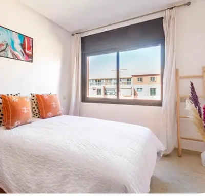 a bedroom with a white bed and a large window at Appart cosy centre-ville piscine et terrasse in Marrakech