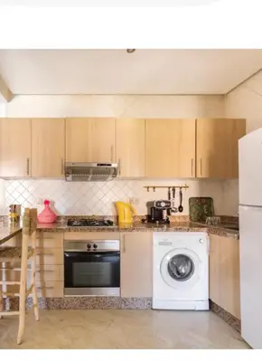 a kitchen with a stove and a washing machine at Appart cosy centre-ville piscine et terrasse in Marrakech