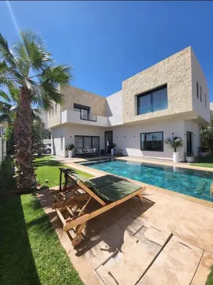 a house with a swimming pool and a palm tree at Villa de luxe, Piscine chauffée, Petit Déjeuner, Hammam, Ménage, Proche centre de Marrakech in Marrakech