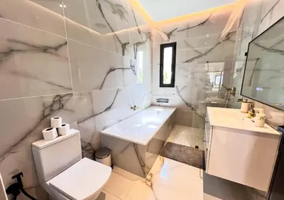 a white bathroom with a toilet and a sink at Villa de luxe, Piscine chauffée, Petit Déjeuner, Hammam, Ménage, Proche centre de Marrakech in Marrakech