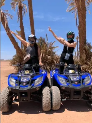 two women are standing on atvs in the desert at Premium Stay in Marrakech