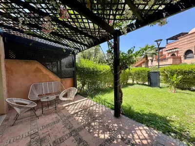 a patio with two chairs and a table and grass at Garden Villa-Style Retreat with Patio, BBQ & Pools in Marrakech