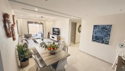 a dining room and living room with a table and chairs at Apartment Coralia - Pool - Terrace in Marrakech