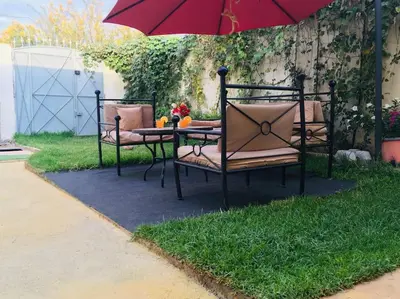 a table and chairs with an umbrella on the grass at DaR CHAMSS in Marrakech