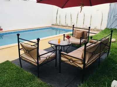 a table with two chairs and an umbrella next to a pool at DaR CHAMSS in Marrakech