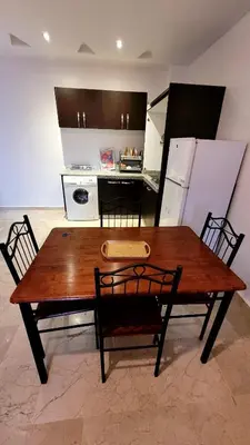 a kitchen with a wooden table and chairs and a kitchen with a counter at Appartement 29 avec balcon pour famille in Marrakech