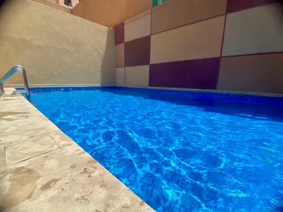 a swimming pool with blue water in a building at Les marguerites avec piscine près du jardin majorelle in Marrakech