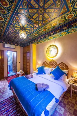 a bedroom with a large bed with a painted ceiling at Riad Almonds Marrakech in Marrakech