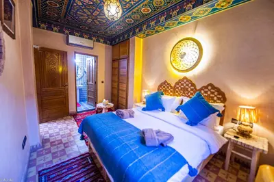 a bedroom with a large bed with blue pillows at Riad Almonds Marrakech in Marrakech