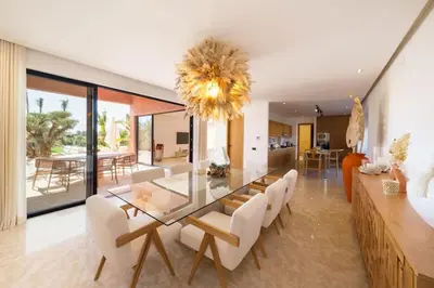 a dining room with a glass table and white chairs at Dar Al Jenna - Villa de luxe avec piscine privée in Marrakech