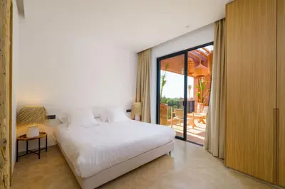 a bedroom with a white bed and a sliding glass door at Dar Al Jenna - Villa de luxe avec piscine privée in Marrakech