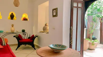 a living room with a table and a red chair at Authentique riad Emplacement exceptionnel in Marrakech