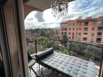 a balcony with a table and a chandelier at Appart 2 chambres luxe contemporain hivernage in Marrakech