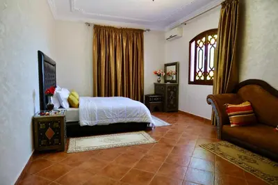 a bedroom with a bed and a couch and a window at Villa Les Terrasses Des Jardins in Marrakech