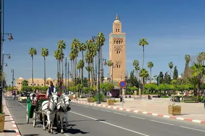 a horse drawn carriage on a city street with a clock tower at Maison d'hôtes Marrakech in Marrakech