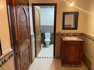 a bathroom with a toilet and a sink and a wooden door at Maison d'hôtes Marrakech in Marrakech