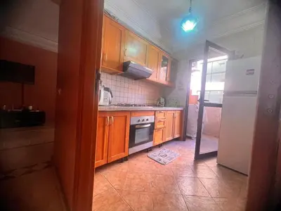 a kitchen with wooden cabinets and a white refrigerator at prestige andalouse 4 in Marrakech