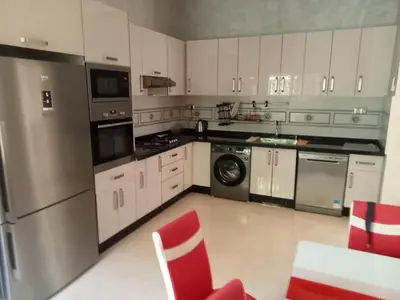 a large kitchen with white cabinets and red chairs at golf amelkis médina 1 N 50 in Marrakech