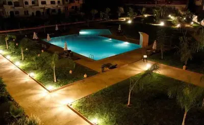 a large swimming pool at night with lights at Somptueux appartement avec terrasse et piscines in Marrakech