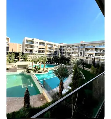 an apartment complex with a swimming pool and palm trees at AMIZING Apartments Marrakech WAZO in Marrakech