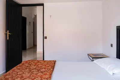a bedroom with a white bed and a door to a hallway at Hotel Apart HLB in Marrakech