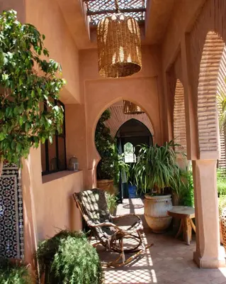a patio with a chair and potted plants and a chandelier at Dar Anacaona in Marrakech
