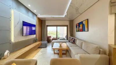 a living room with a couch and a tv at Prestigia 2 chambres vue piscine agate in Marrakech