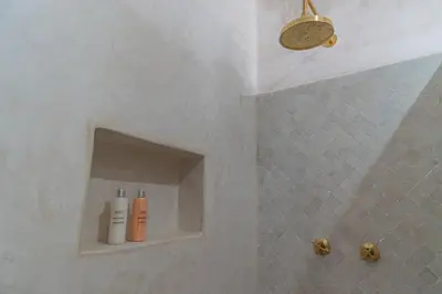a bathroom with a shower with two bottles on a shelf at Riad COPAH in Marrakech