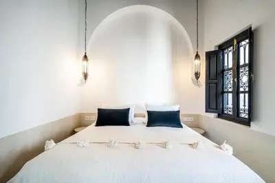 a bedroom with a white bed with two blue pillows at Riad COPAH in Marrakech