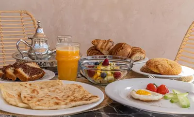 a table with plates of breakfast food and orange juice at Riad COPAH in Marrakech