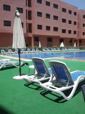 a group of lawn chairs and an umbrella next to a pool at Ruime 2 kamer appartement 5 min van het centrum in Marrakech