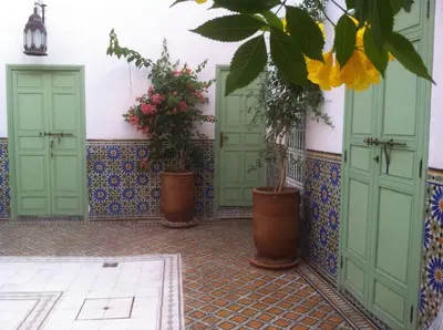 a courtyard with three green doors and potted plants at Riad Charij in Marrakech