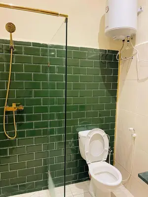 a green tiled bathroom with a toilet and a shower at Soleil de Medina in Marrakech