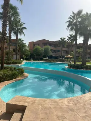 a large swimming pool with palm trees in a resort at Prestigia corail in Marrakech