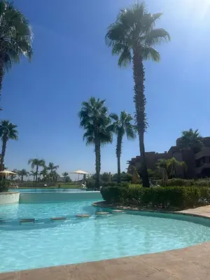 a swimming pool with palm trees in the background at Prestigia corail in Marrakech