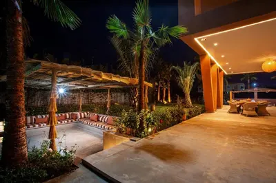 a patio with a pool and palm trees at night at Villa Saphia K in Marrakech