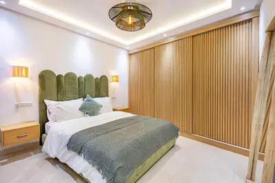 a bedroom with a large bed with a green headboard at Verdelune Apartments in Marrakech