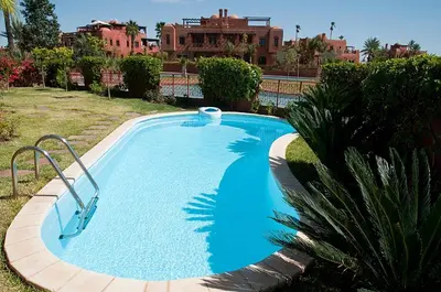 a large blue swimming pool in front of a building at Palacio Hôtel Condominium Marrakech in Marrakech