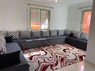 a living room with a black couch and a carpet at Apparemment in Marrakech