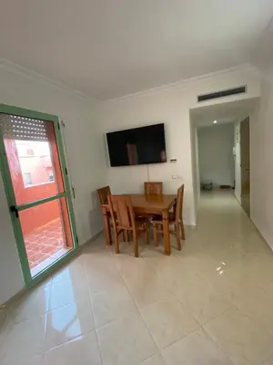 a dining room with a table and a television on the wall at Apparemment in Marrakech