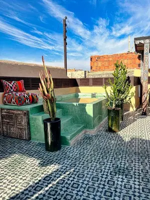 a patio with a swimming pool and two potted plants at Riad dar darcom in Marrakech