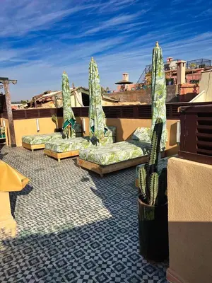 a group of beds on a roof with a cactus at Riad dar darcom in Marrakech