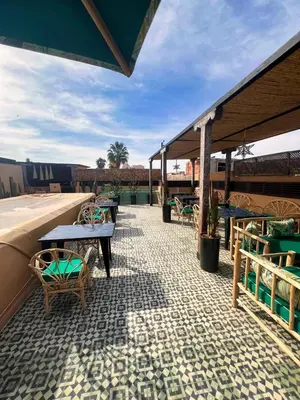 a patio with tables and chairs on a tile floor at Riad dar darcom in Marrakech