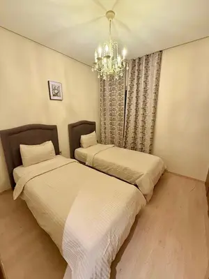 two beds in a bedroom with a chandelier at Prestigia Marrakech golf city appartement 3 chambre in Marrakech