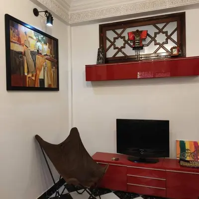 a living room with a television and a red dresser at Appartement T3 Le petit chat in Marrakech