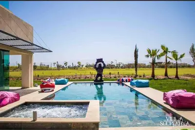a swimming pool with a clock in the middle at Magnifique villa sur front de golf Amelkis in Marrakech
