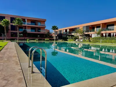 a swimming pool in front of a building at Noria cosy & chic jardin privé in Marrakech