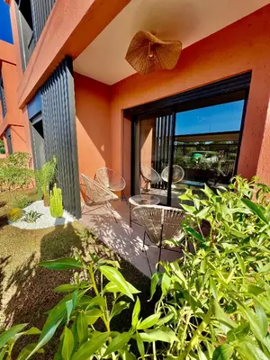 a patio with a table and chairs and a large window at Noria cosy & chic jardin privé in Marrakech