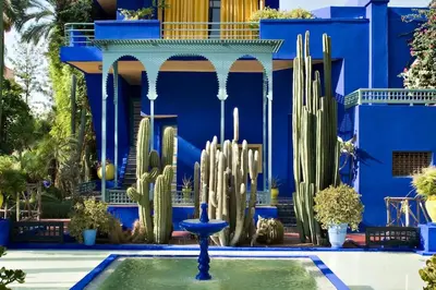 a blue building with a fountain and cactuses in front at Feel At Home Heart Of Marrakech in Marrakech
