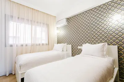 two beds in a small room with a window at Feel At Home Heart Of Marrakech in Marrakech